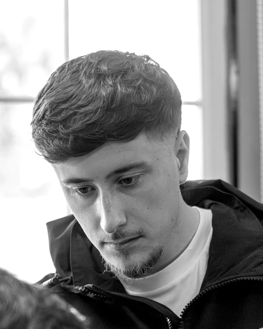 One of our barbers concentrating on a cut, in black and white