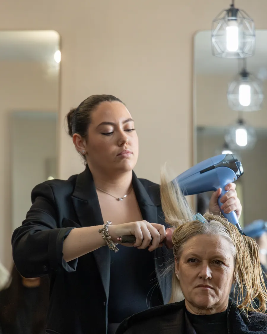 A hairdresser blow-drying a client's blonde hair
