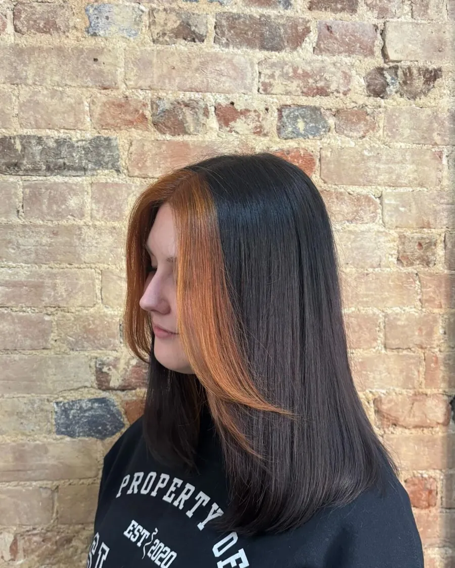 Sleek dark hair with a copper money-piece against the studio's brick wall
