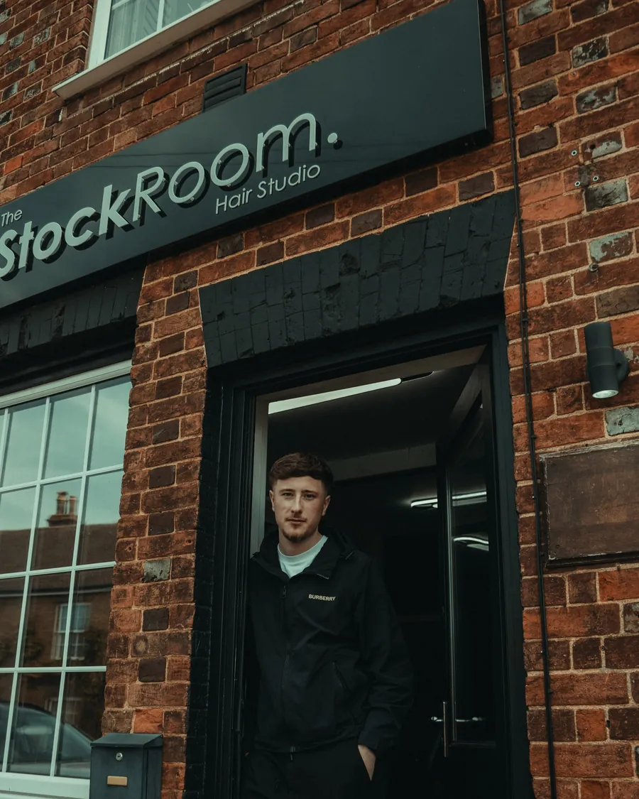 One of our barbers in the doorway of the black StockRoom shopfront on Henlow High Street