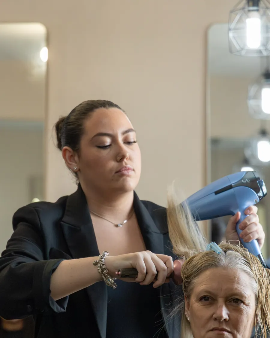A hairdresser blow-drying a client's hair at The StockRoom